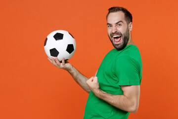 Side view overjoyed man football fan in green t-shirt cheer up support favorite team with soccer...