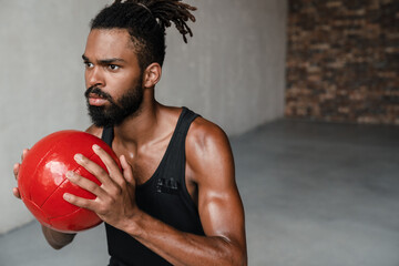 Image of african american sportsman working out with medicine ball