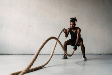 Image of african american sportsman working out with battle ropes - obrazy, fototapety, plakaty
