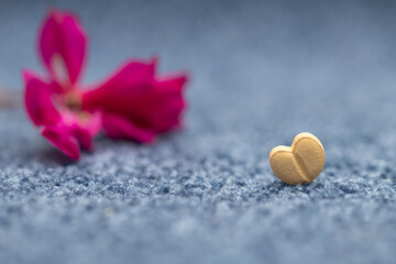 Fototapeta premium heart shaped tablet with flower and blurred blue cloth background