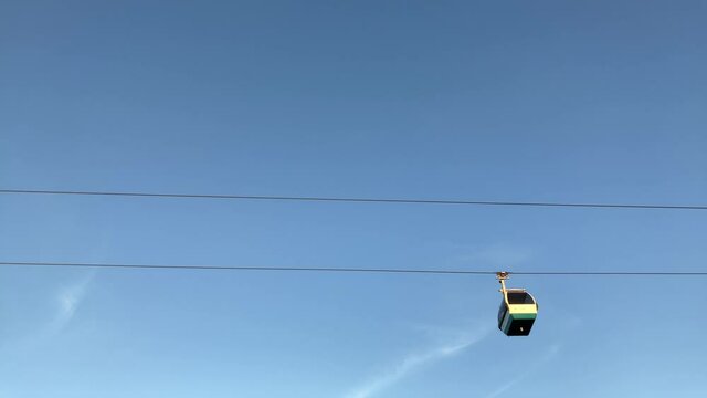 4k footage of the touristic cable car flying over the Tagus riverside in the city of Lisbon at sunset. Blue sky background with scattered clouds. Travel touristic concept lifestyle.