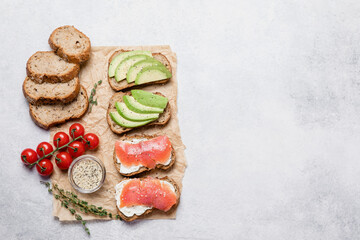 Variety of rye bread toasts with avocado, salmon and cream cheese.