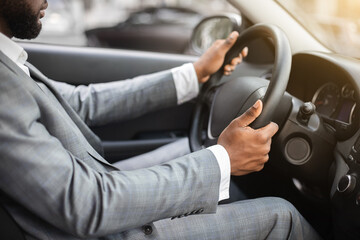 Closeup of black man in suit driving car
