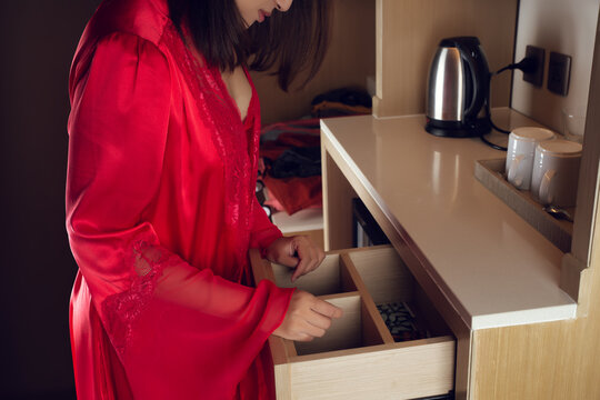 A Woman In A Red Nightgown Opens A Drawer To Find Something In The Kitchen. Can't Find, Lost Items