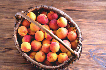 Natural ripe apricots in a wicker basket on a natural wooden background, top view