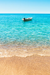 Fototapeta na wymiar Uninhabited beach overlooking the ocean - lonely white boat in the water - tropical paradise