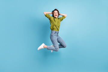 Fototapeta na wymiar Photo portrait of excited woman jumping up holding head with hands isolated on pastel light blue colored background