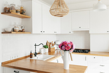 View on clean white simple modern kitchen in scandinavian style, aster Michaelmas daisy bouquet in vase on the table