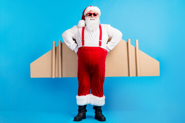 Full length photo of crazy overweight santa claus with big stomach have craft wings fly x-mas christmas party wear suspenders overall sunglass boots isolated blue color background