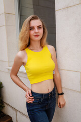 Portrait shooting of a stylish girl. Beige shades. Trends of spring and summer 2020.Black pants and yellow top.