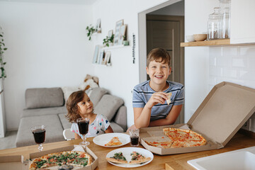 Happy time of eating concept. Kids boy and girl eating pizza at home.