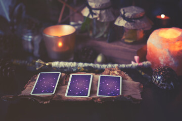 3 Tarot cards spread lying on a black table with magic items. Toned to cold colors in shadows. - obrazy, fototapety, plakaty