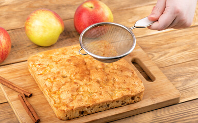 A sieve in a woman's hand for sprinkling apple pie with cinnamon.