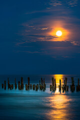 Great moonlight in blue sky with reflection over the sea till the coast