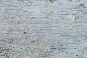 The texture of an old surface covered with white paint, cracked and peeling from time.