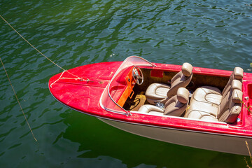 Obraz premium Part view of old red motor boat with leather seats on a calm lake water surface