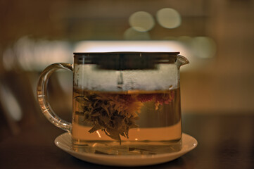 Glass teapot of invigorating fresh fragrant tea on a brown wooden table.