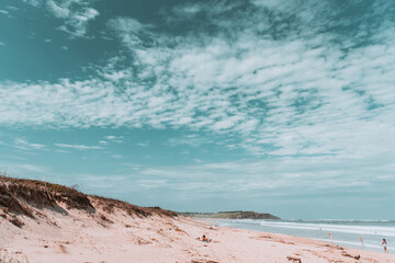 Sunset at the beach with clouds spread in the sky and calm waves of water of the ocean in the background