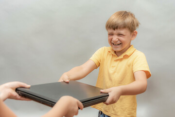 A naughty boy, addicted to computer games, snatches a laptop out of his parents' hands.