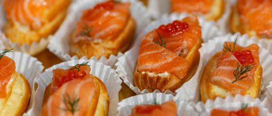 Canapes with red fish and caviar. Beautiful festive table setting. Panorama format. Close-up.
