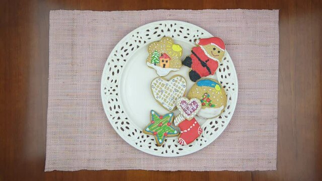 White porcelain plate full of ginger cookies on a wooden table and pink tablecloth. Every one second, one by one, cookies are disappearing. Last cake is a heart figure.