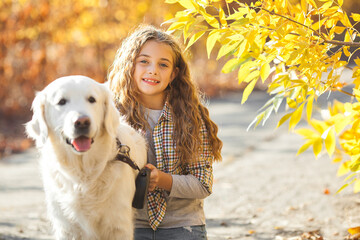 Pretty little girl with her pet on autumn background