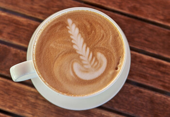 Drawing on the coffee foam. White saucer and cup with coffee, top view