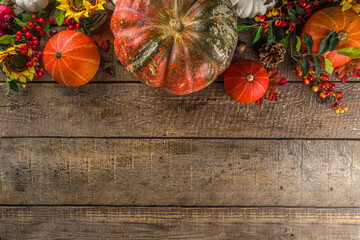 Festive autumn background, with traditional decor - pumpkins, berries, fruits, leaves on old wooden background. Thanksgiving day and Halloween holiday greeting card concept. Autumn flatlay
