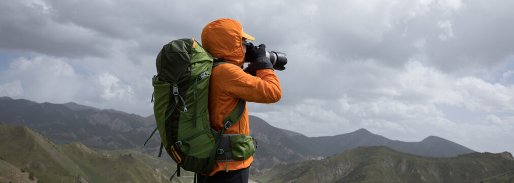 Successful woman photographer  taking photo on high altitude mountain top