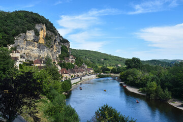 Fototapeta na wymiar Village of houses on the mountainside and a river surrounded by nature. La Roque-Gageac, France 