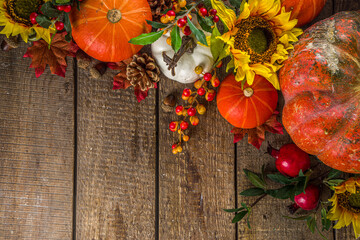 Festive autumn background, with traditional decor - pumpkins, berries, fruits, leaves on old wooden background. Thanksgiving day and Halloween holiday greeting card concept. Autumn flatlay