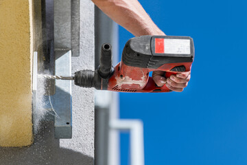 Working power hammer drill. Anchoring of steel construction into building masonry. Hand holding...