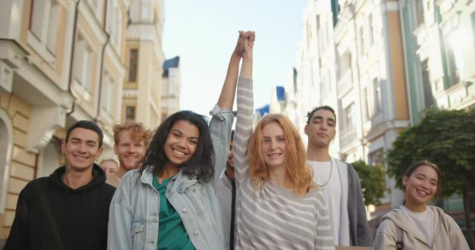 Two happy mixed races women lift hands up together in a mass protest against racism.