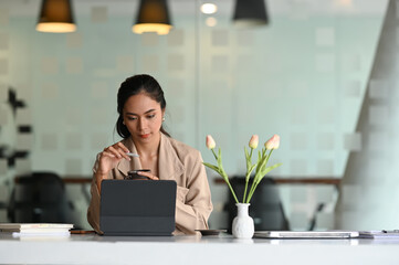 Young attractive businesswoman searching the data on internet with computer tablet in office.