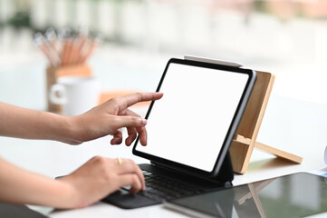 Young businesswoman planing her strategy while typing on computer tablet with white screen in...