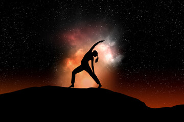woman silhouette in yoga position against a black starry sky with copy space for your text