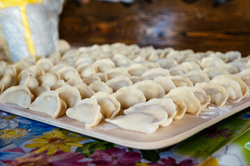 fresh blinded dumplings lie in rows on wooden board. hand sculpting dumplings.