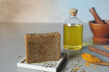 organic natural herbal handmade soap in ceramic tray on table with olive oil turmeric powder, cinnamon stick and mortar with background of cement wall in the workshop classroom of diy handmade soaps