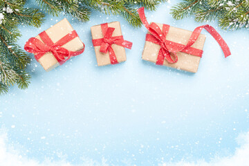 Christmas gift boxes and fir tree over blue background