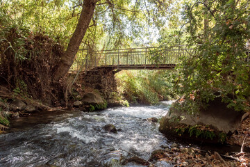 Fototapeta na wymiar The bridge over the swift mountainous Hermon River with crystal clear waters in the Golan Heights in northern Israel
