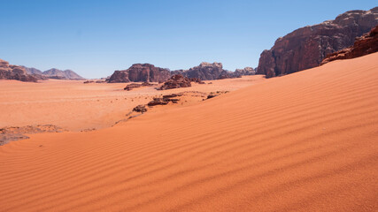 Fototapeta na wymiar sand dune in the background of cliffs in the Wadi Rum Desert Jordan. Hot Sandy landscape.