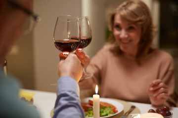 Close-up of couple toasting with glasses of red wine at the table