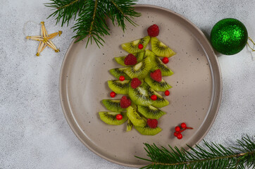 Kiwi fruit tree decorated with raspberry Hades on top of flat lay. New year's food