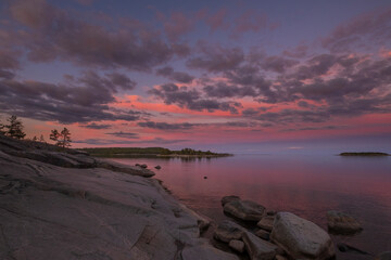 Beautiful sunset on Lake Ladoga in Karelia, Russia in the Ladoga Skerries national park in summer. Natural landscape with water rocks, stone islands and forest
