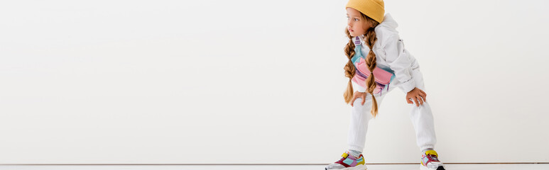blonde girl in sportswear posing near white wall, panoramic shot