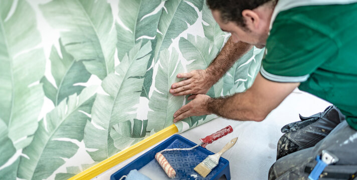 flei&szlig;iger Handwerker bringt eine Mustertapete an die Wand an