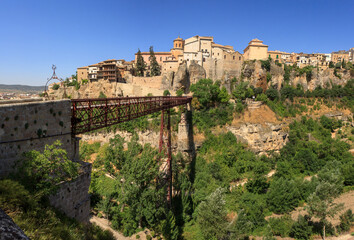 Fototapeta na wymiar Old town of Cuenca, Spain, seen from the other side of the canyon (hoz) of the Huécar river near the iron San Pedro pedstrian bridge. To the left the famous hanging houses (cases colgadas).