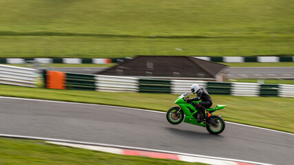 A panning shot of a racing bike on one wheel as it circuits a track. - obrazy, fototapety, plakaty