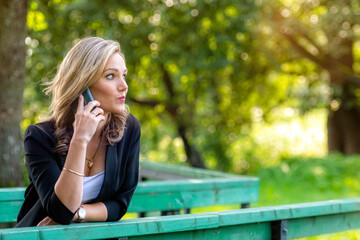 a young emotional blonde woman in the park talking on the phone