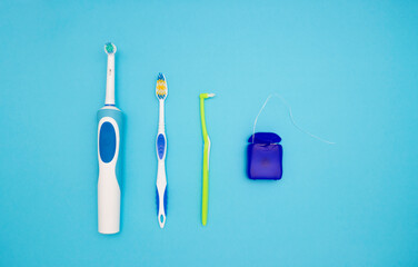 Oral hygiene. Electric toothbrush brush with toothbrush and dental floss on a blue background. The view from the top.